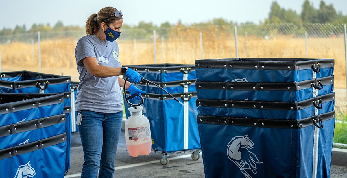 Woman sprays disinfectant on move-in carts