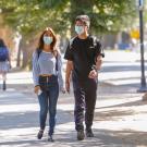 Students with masks walk through the sunlit UC Davis campus.
