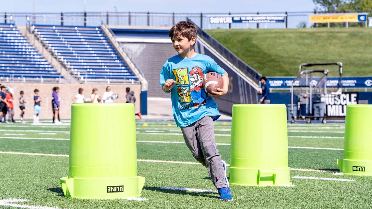 Child runs with football around trash cans