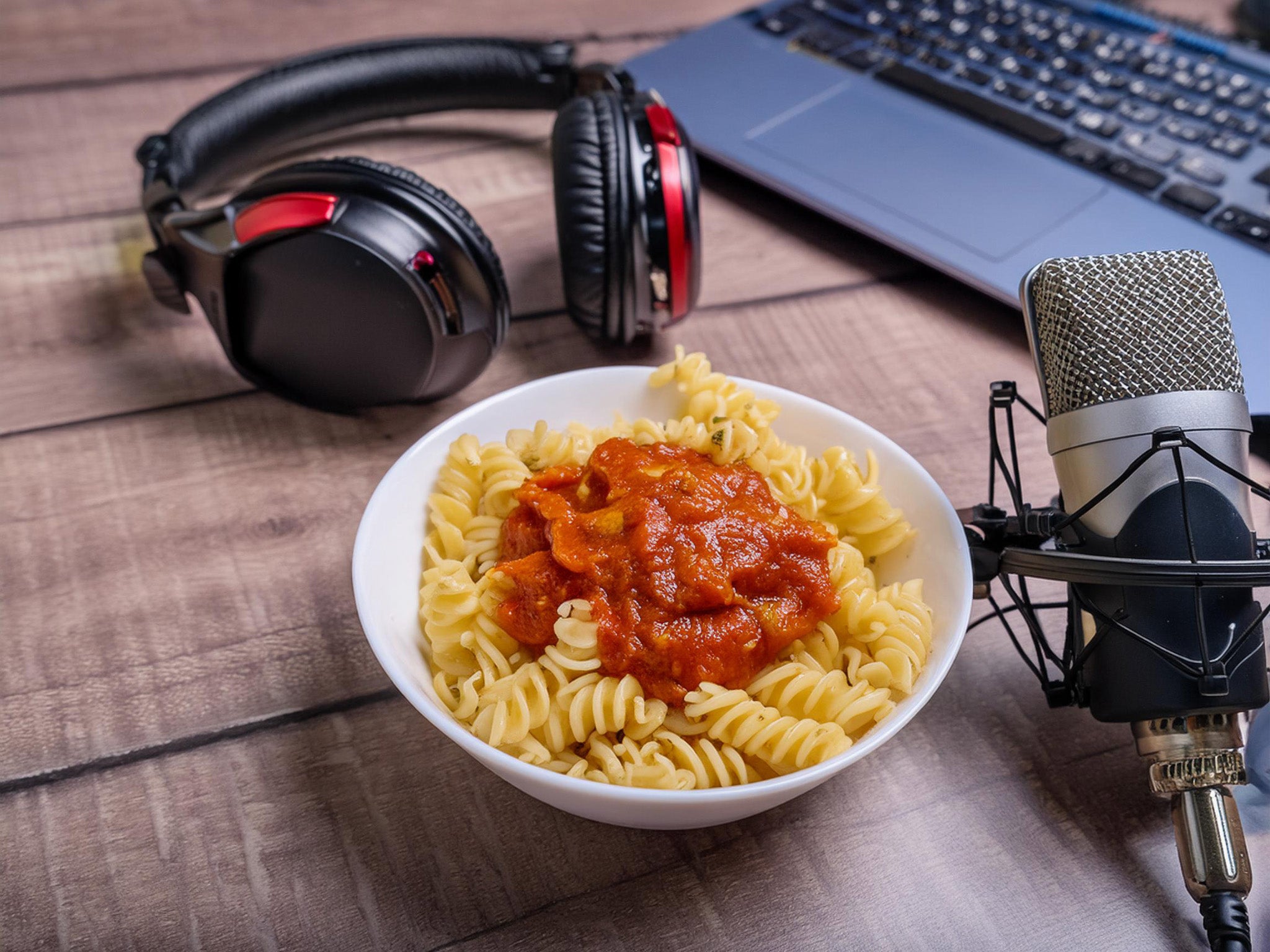 This image of a bowl of spiral pasta next to headphones and a microphone generated entirely by AI. 