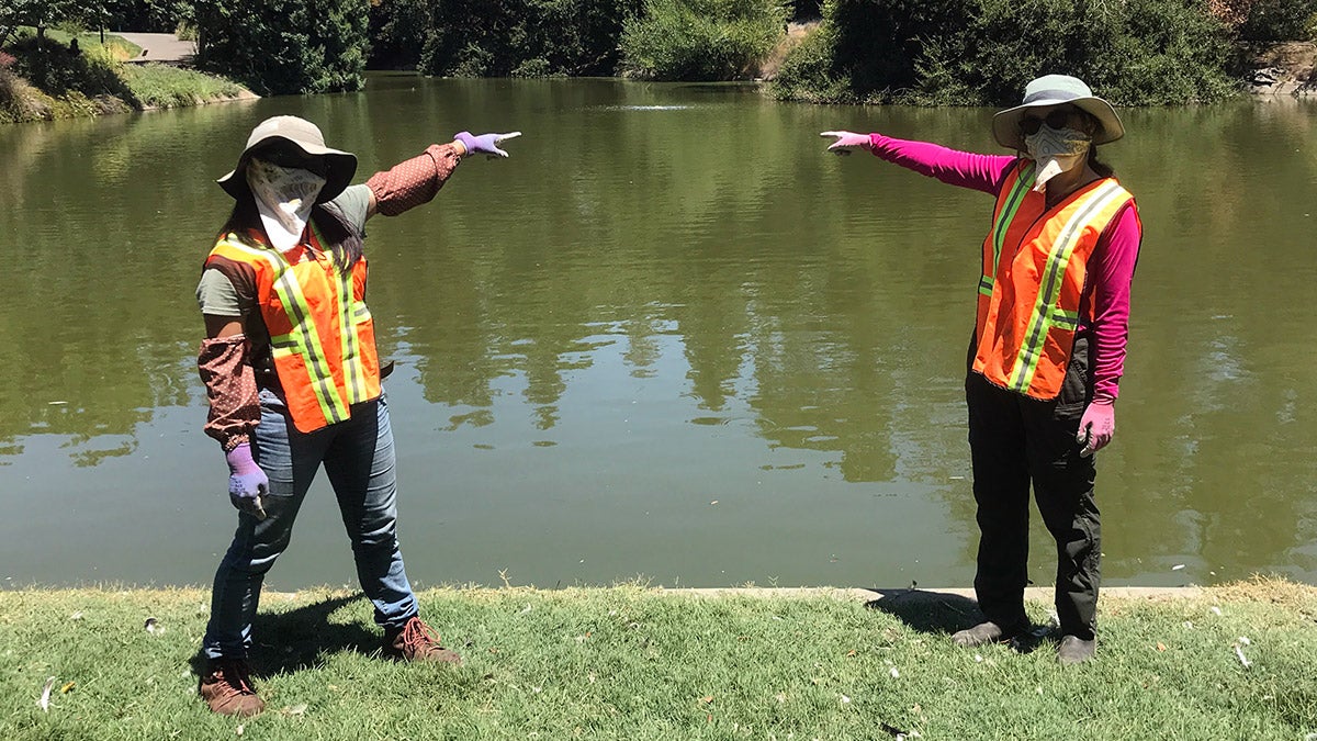 Two people with bandanas point to bubbles in Lake Spafford.
