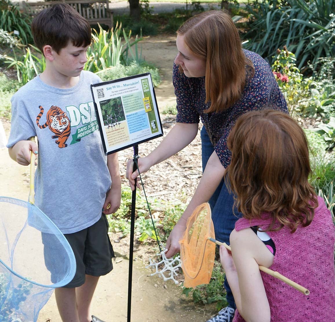 Children look at a garden with a UC Davis student