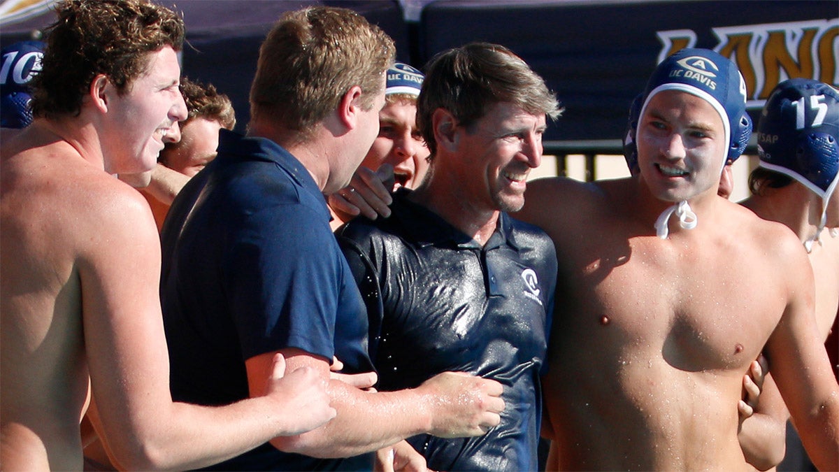 Water polo players surround coach.