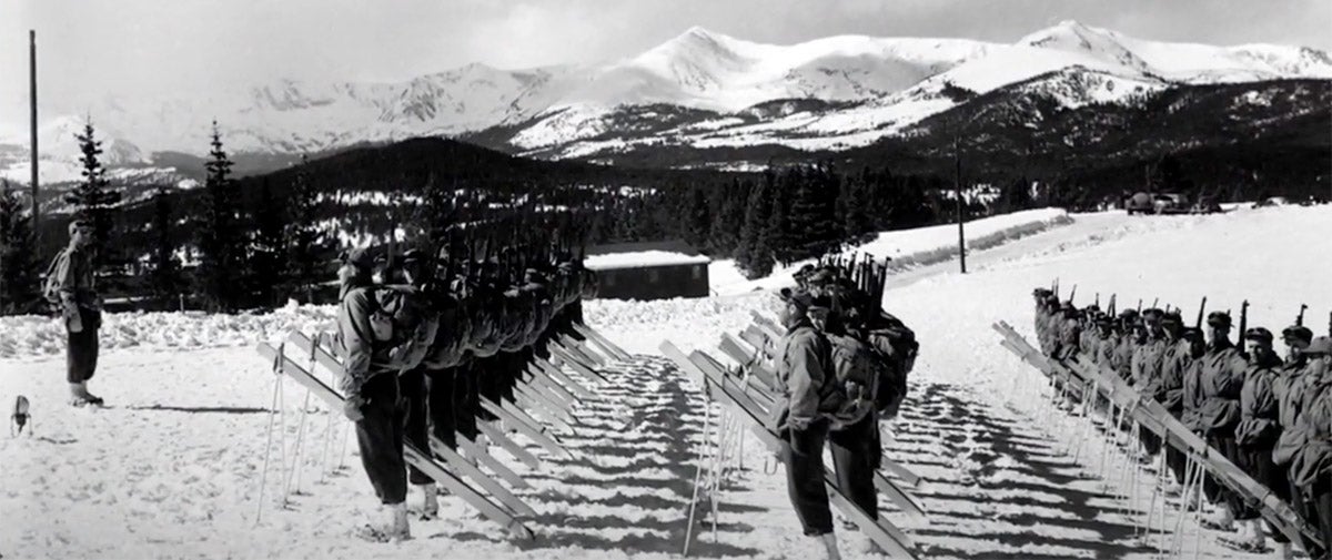 Soldiers stand in rows on snowy mountain.