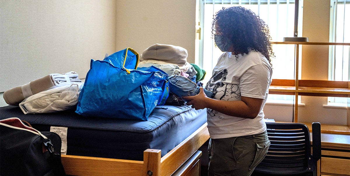 Woman unpacks inside residence hall.