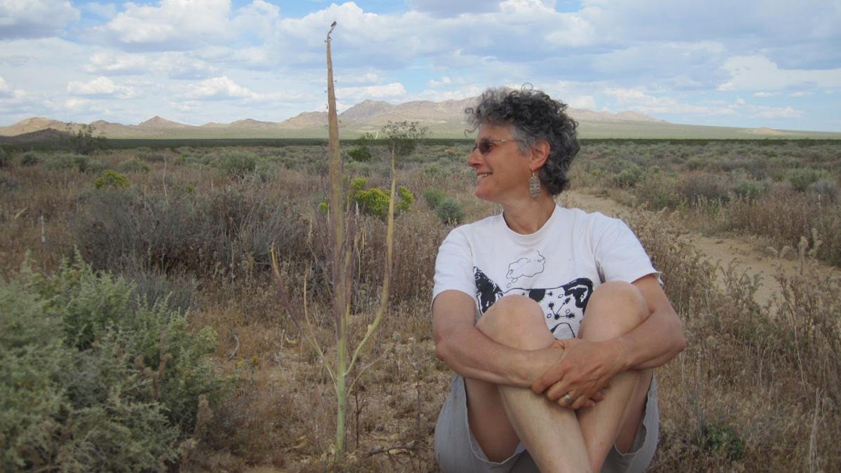 Sharon Strauss, sitting in a field.
