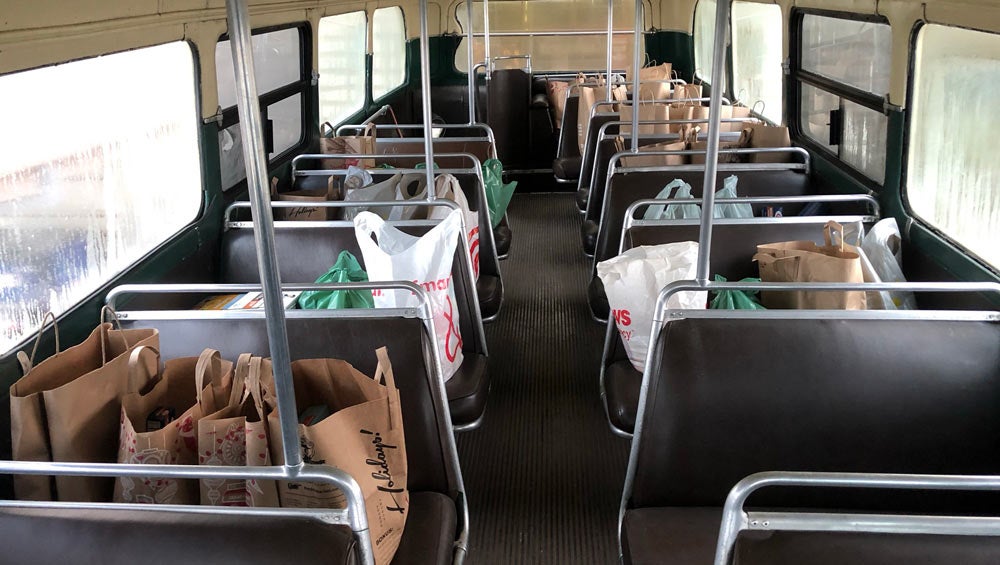 Bags of groceries fill bus seats.