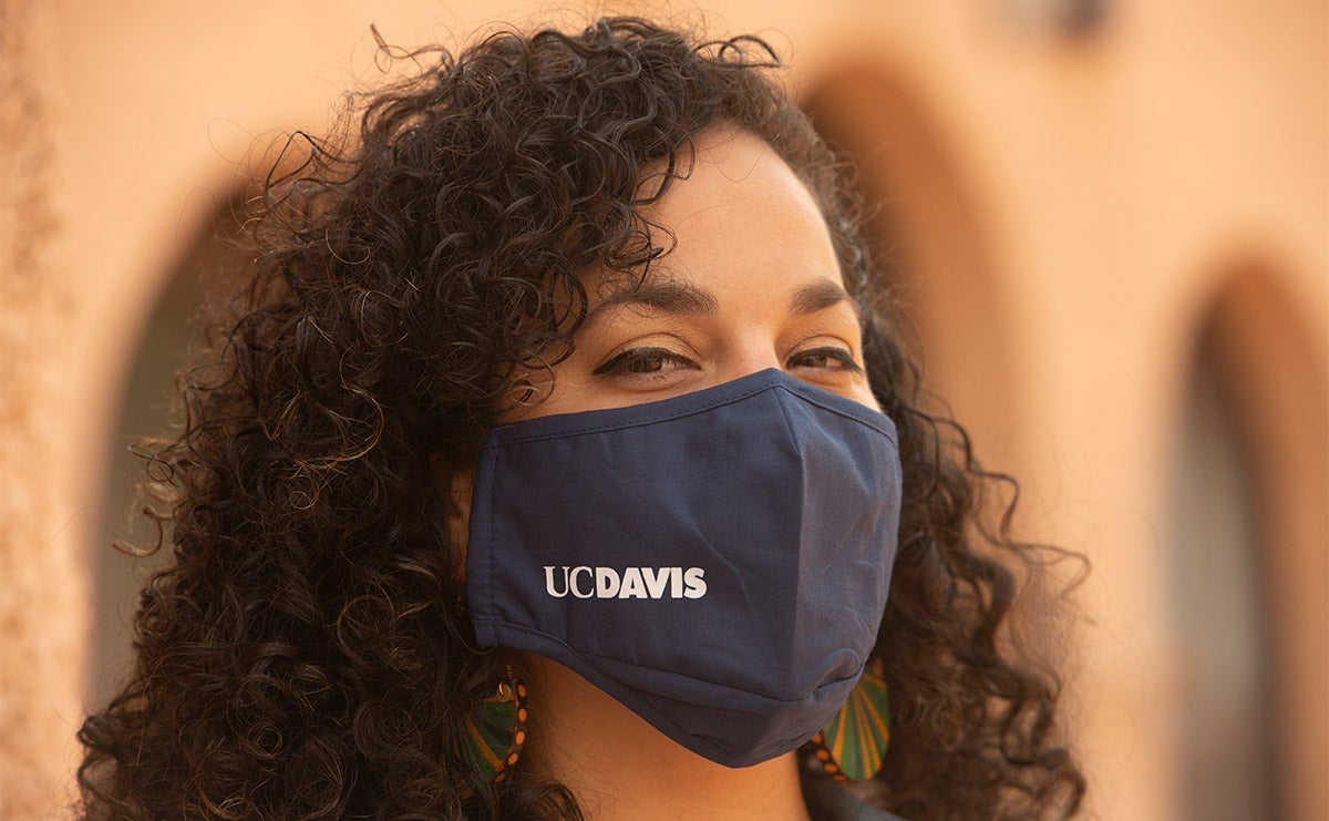 Woman wearing face covering with "UC Davis" branding