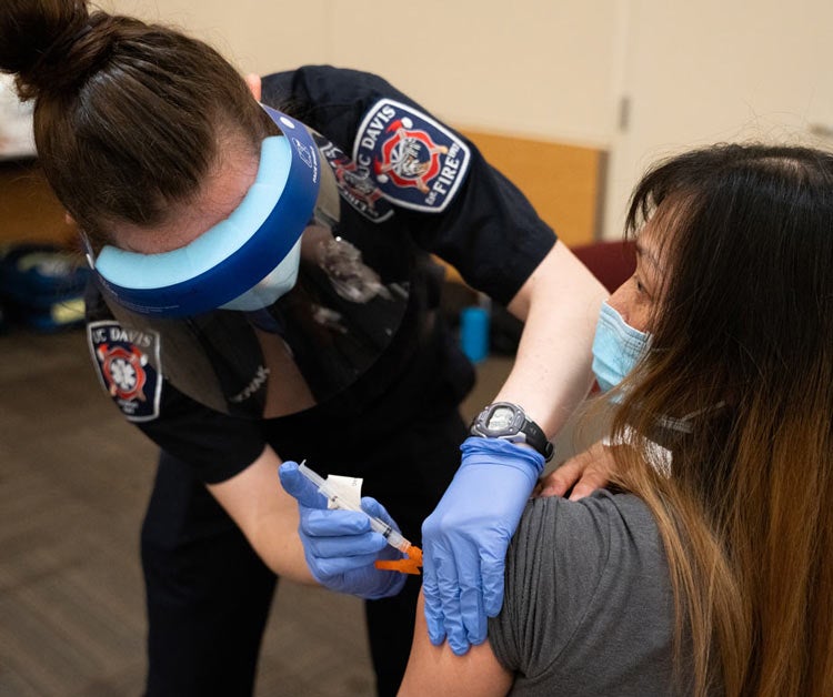 Female student EMT administers vaccination.