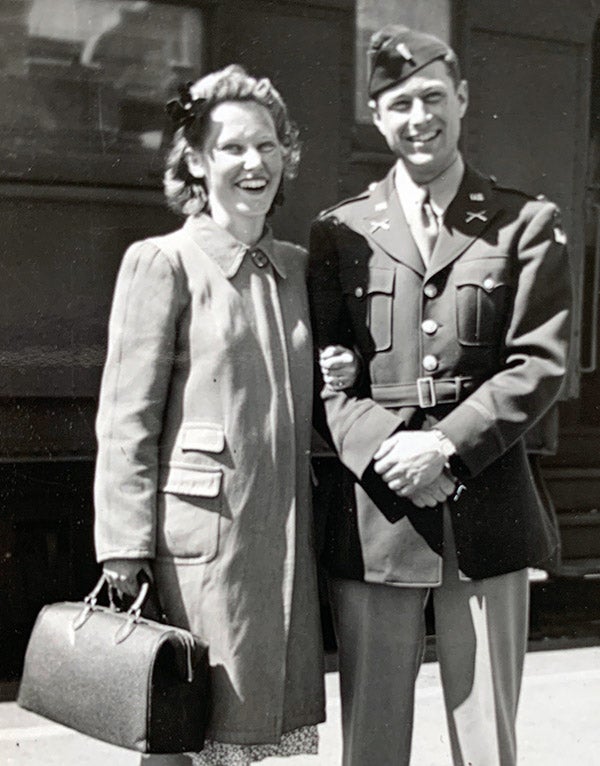 Woman and man stand in front of train in 1943.
