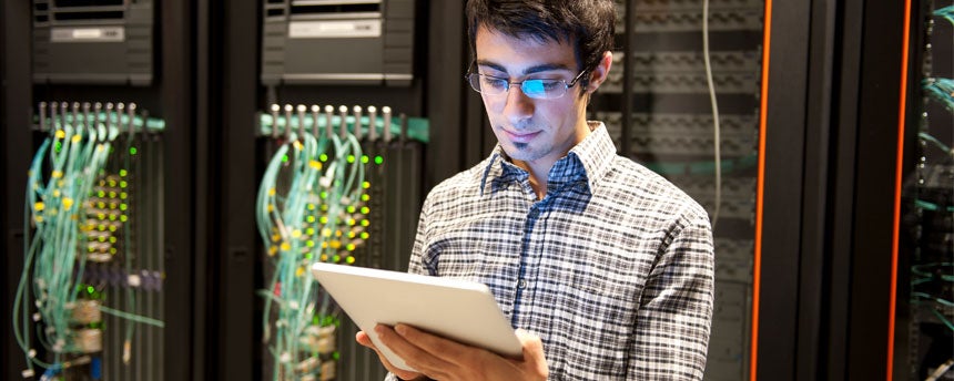 Man looking at tablet in front of servers