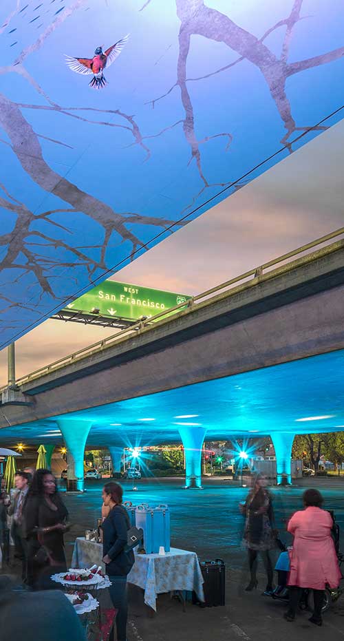 People celebrating under a freeway with its underside painted as a mural