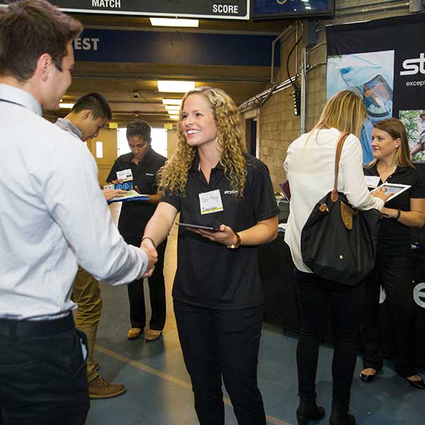 Students talking to business representatives in a big hall.