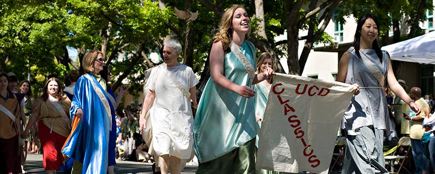 Women marching in a parade holding a banner that says "UCD Classics"