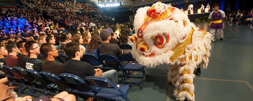 A yellow Chinese lion costume in a big auditorium with people