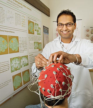 Charan Ranganath, in a lab coat, adjusting wires on a research subject.