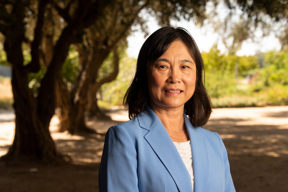 Profile of Professor Ruihong Zhang in blue blazer outside with trees in background