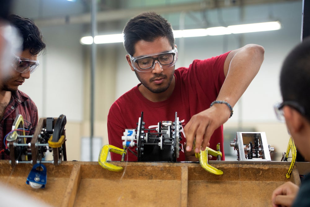 A student in goggles assembles mechanical equipment at UC Davis. 