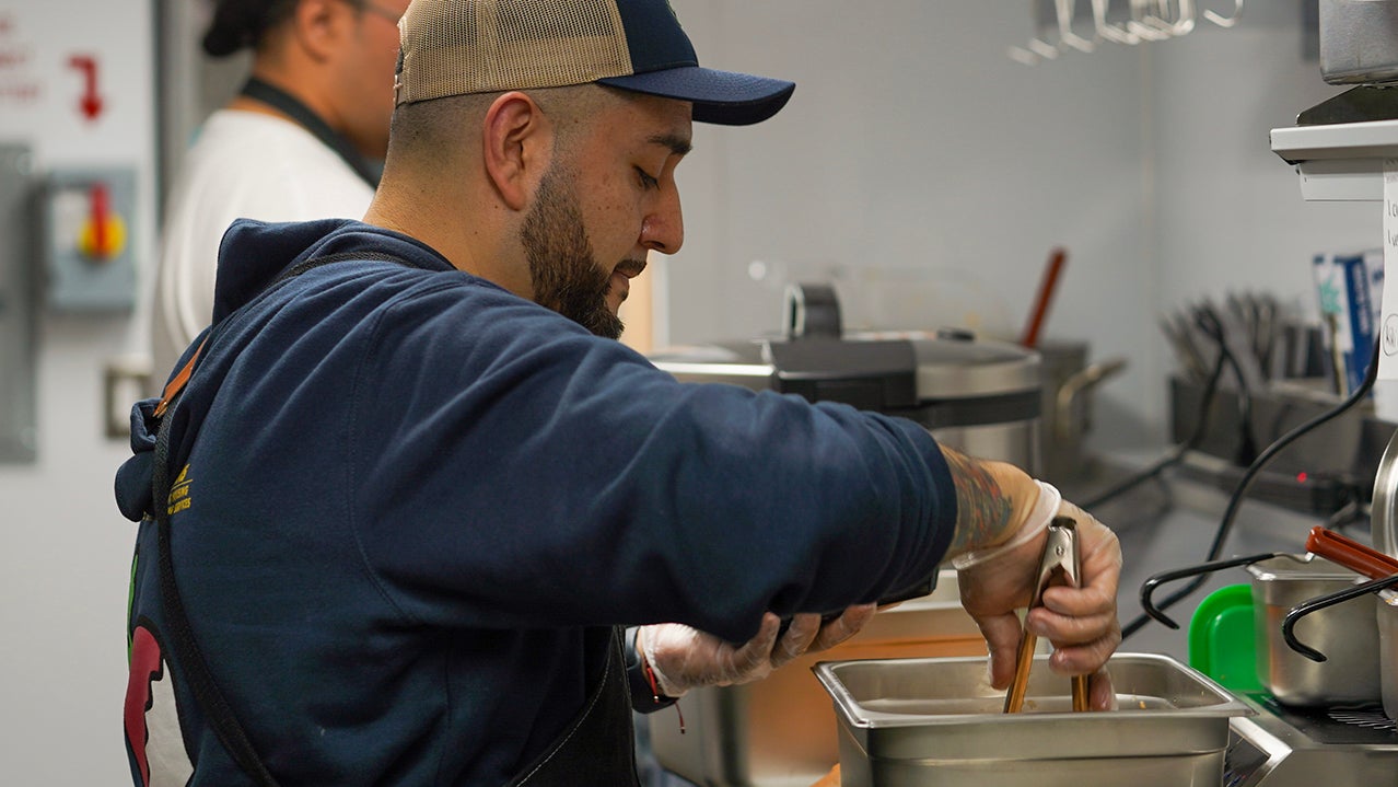 Jesus "Sal" Ramirez dishes up food inside the AggieEats foodtruck.