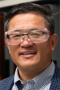Smiling man in clear safety goggles and checked shirt, close-up headshot