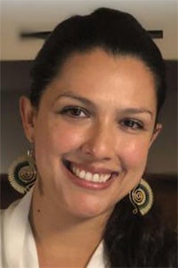Smiling woman with dark hair pulled back, wearing large round patterned earrings
