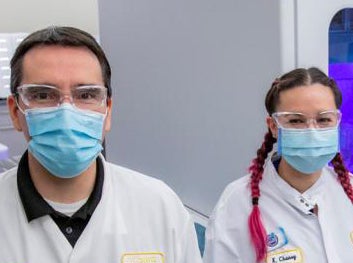 People in lab coats stand and smile