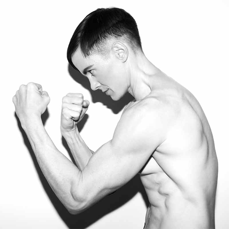 Black-and-white photo of shirtless person in boxing stance, side profile