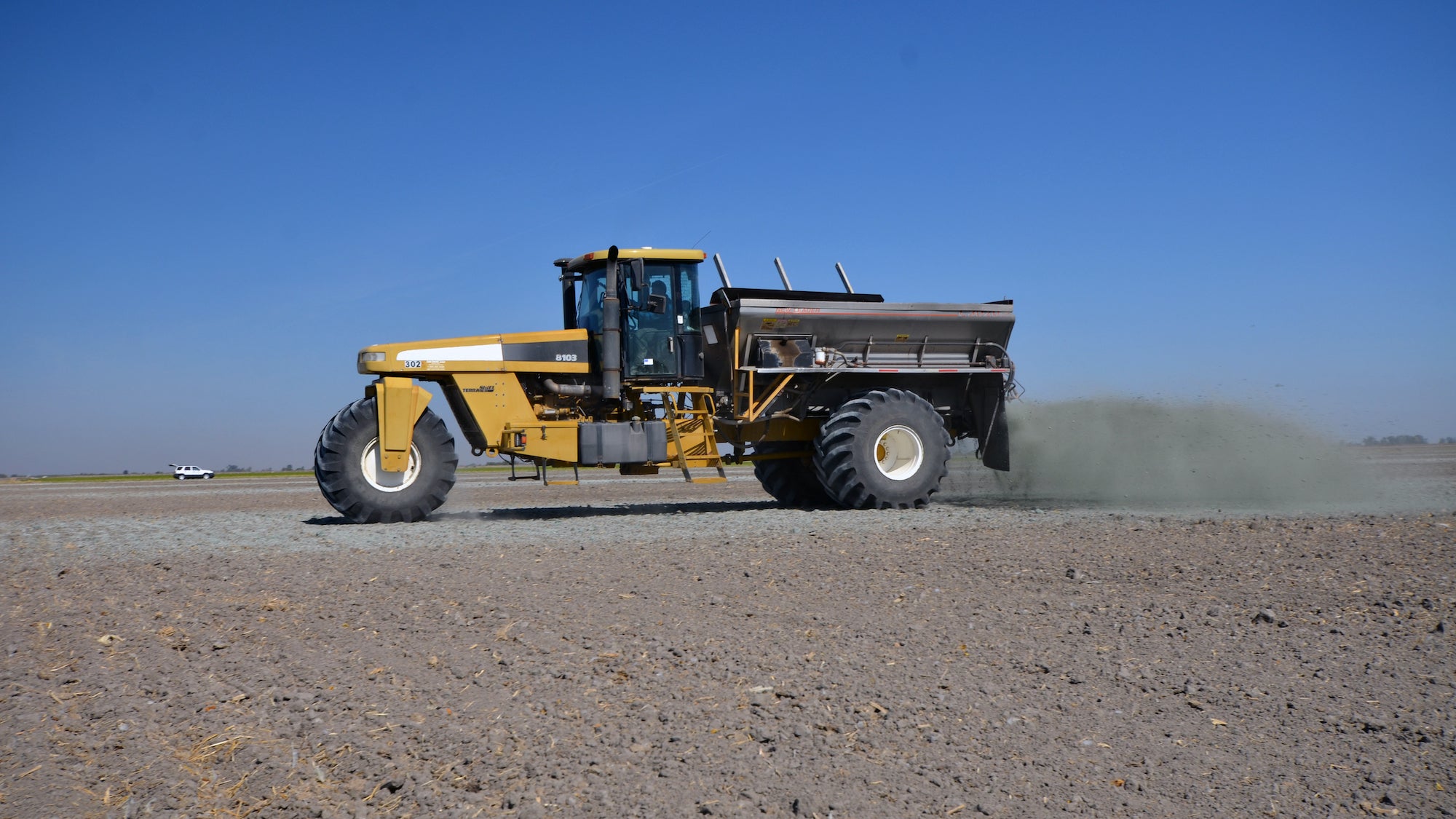 A spreader unloads crushed metabasalt rock on a fallowed corn field in the Central Valley. (Amy Quinton/ UC Davis)