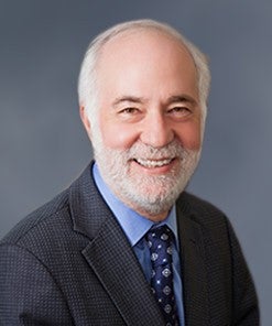 Male caucasian professor head shot in gray suit with gray background