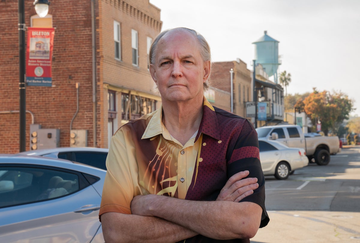 David Kent with arms crossed looks at camera straight ahead with backdrop of downtown Isleton, California
