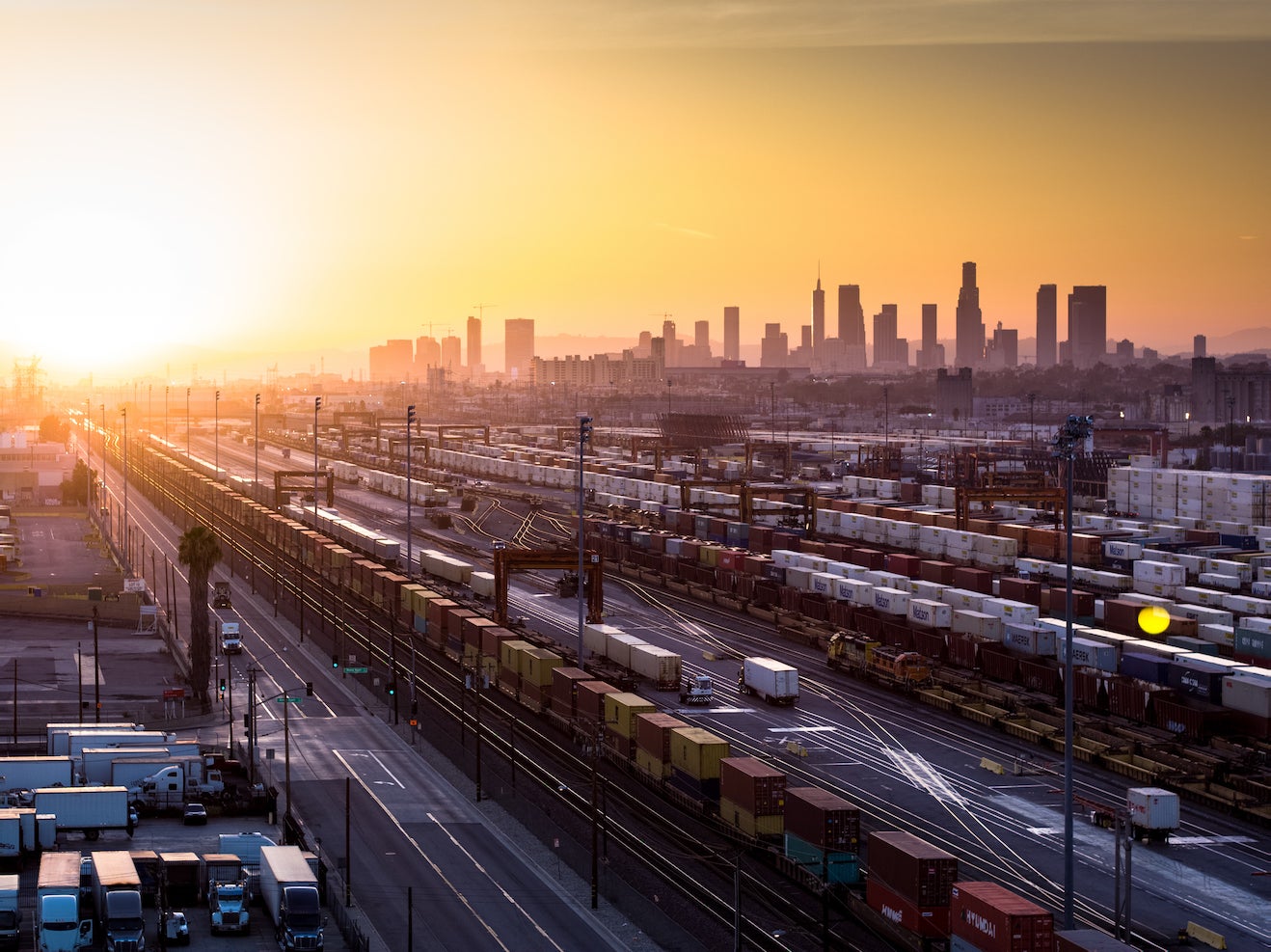 Aerial shot of freight yard with Los Angeles city skyline in backdrop