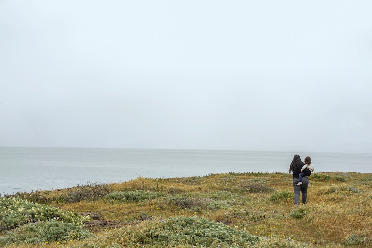 Far off figure of woman holding child looking at ocean at Bodega Bay