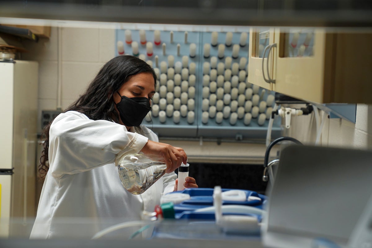 Scientist Alyssa Griffin works in the lab in white lab coat and black mask