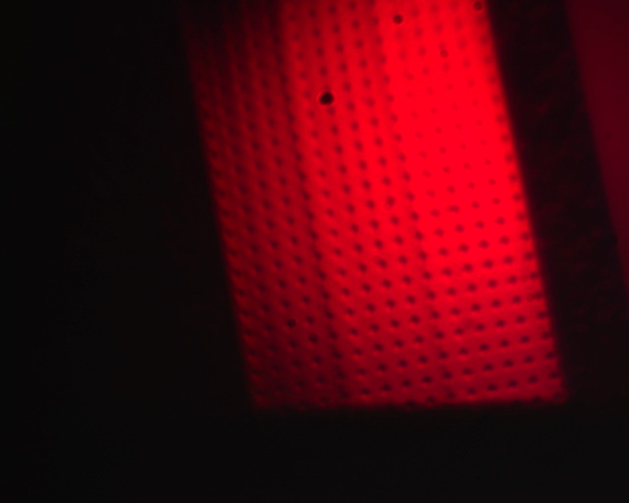 Red backlit infrared sensor with perforated panel and grid of small black holes