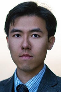 Formal headshot photograph of a man in suit and tie, neutral expression.