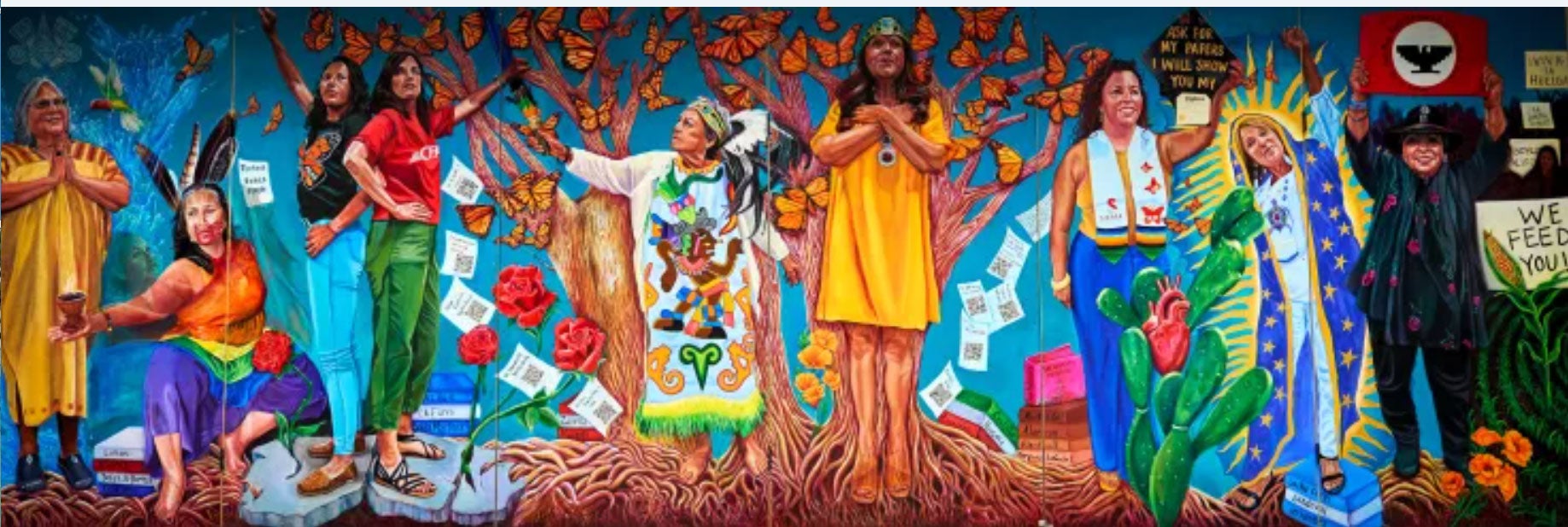 Colorful mural depicting diverse women with symbols of culture and nature, celebrating heritage.