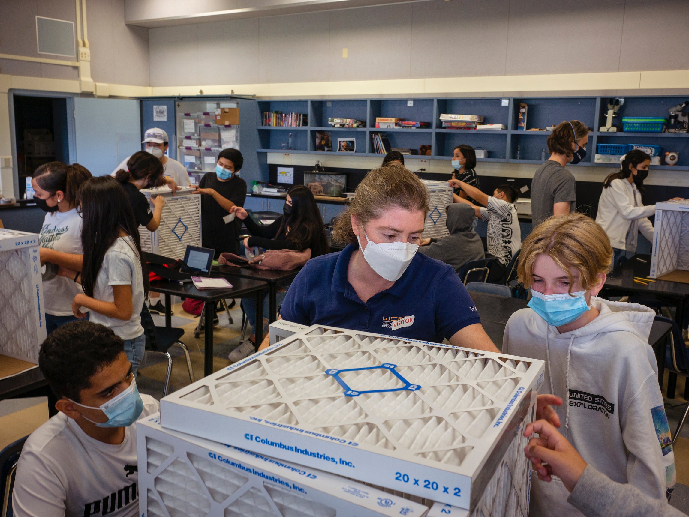 A woman scientist builds air purifier with junior high school students in a classroom