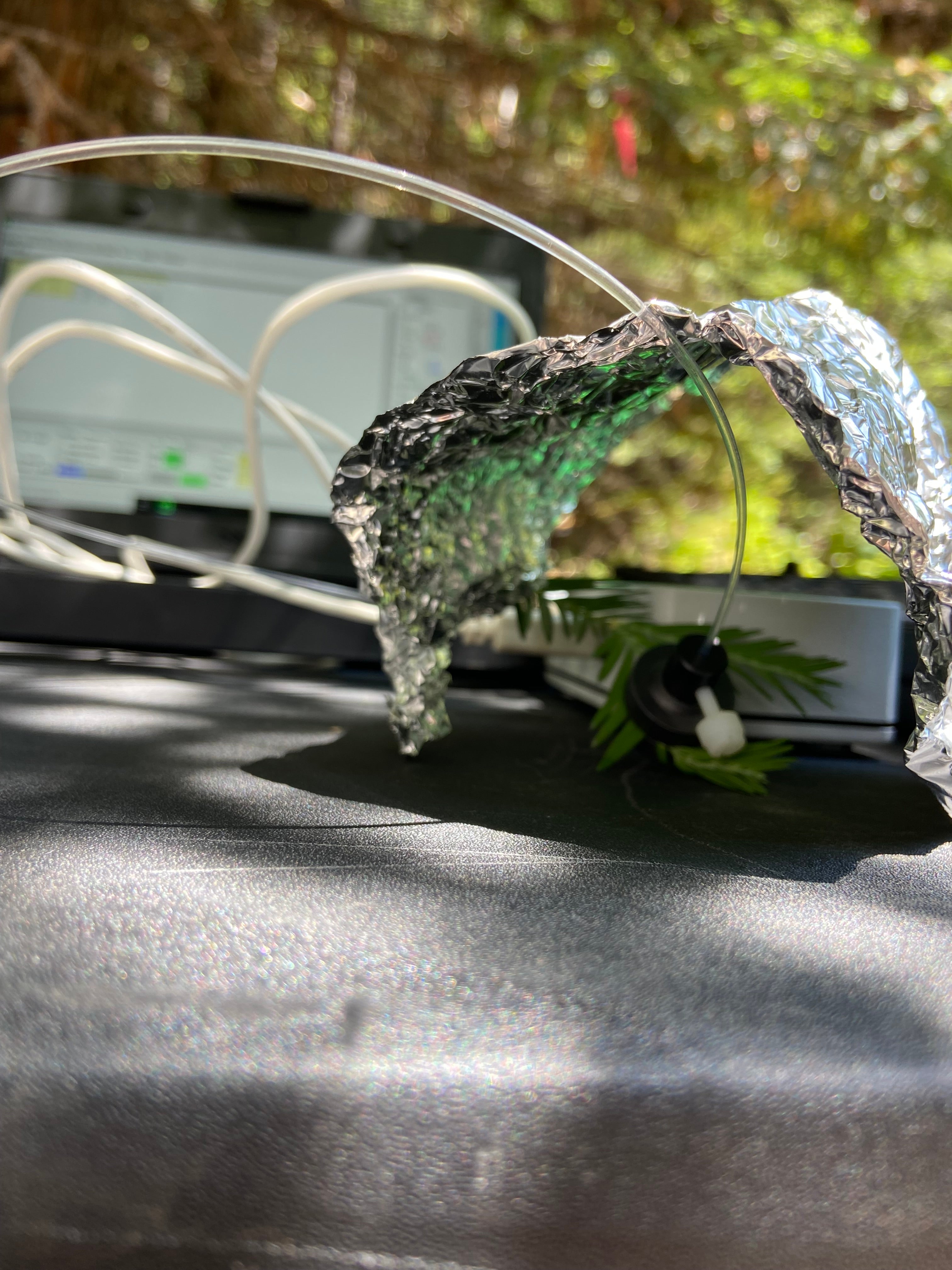 Decorative headband with silver foil, black mesh flower and green ribbon on outdoor table