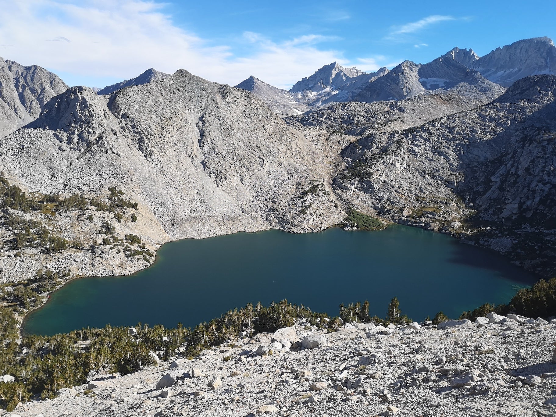 A small alpine lake surrounded by gray mountains in the Sierra Nevada of California