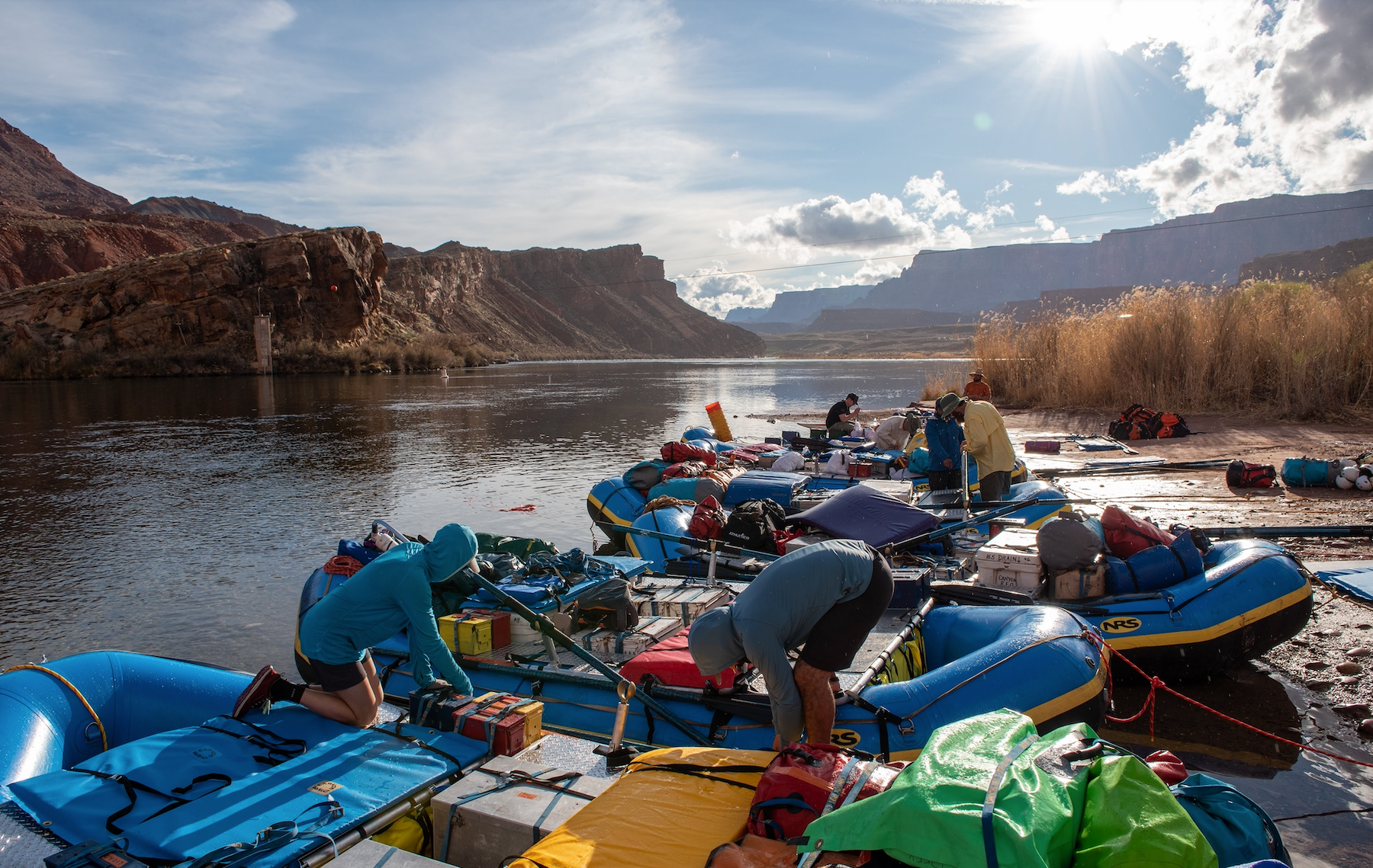 Rafting boats parked at a river in the grand canyon with several people organizing them. 