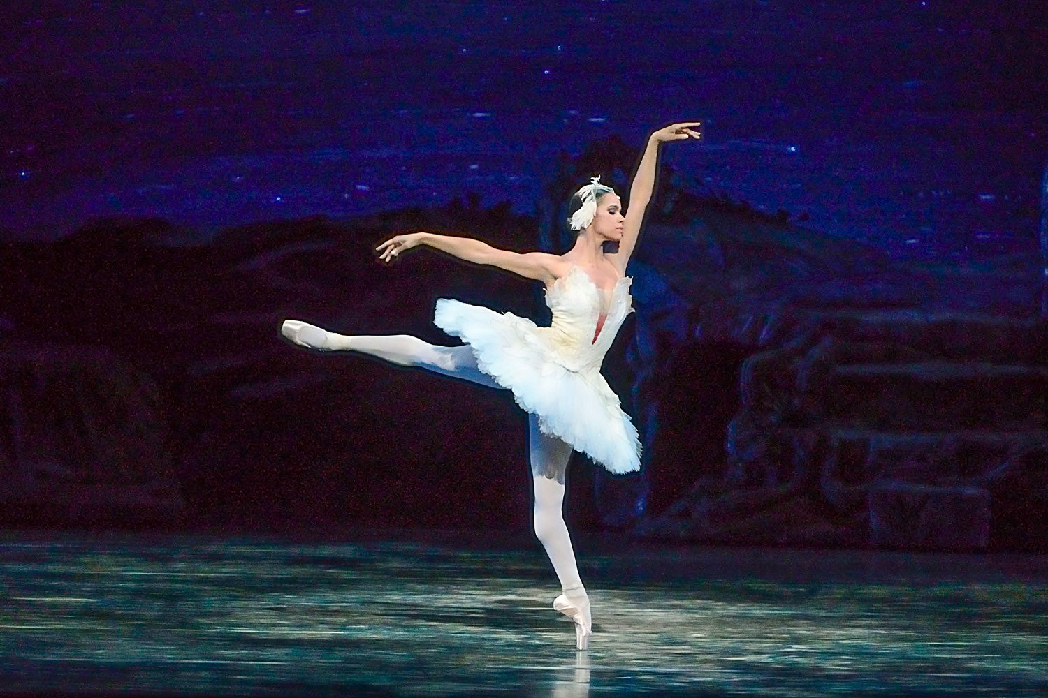Ballerina Misty Copeland  perrforms San Lake on stage in white leotard and tutu, leg and ams extended