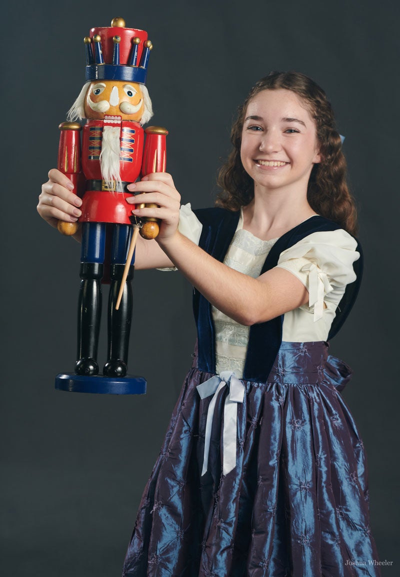 Girl  in costume holding large nutcracker toy in performance,