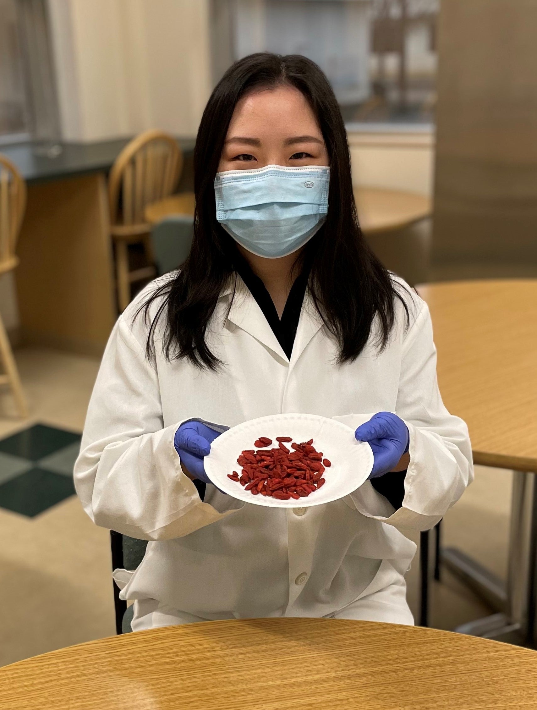 Doctoral student holds small bowl of goji berries