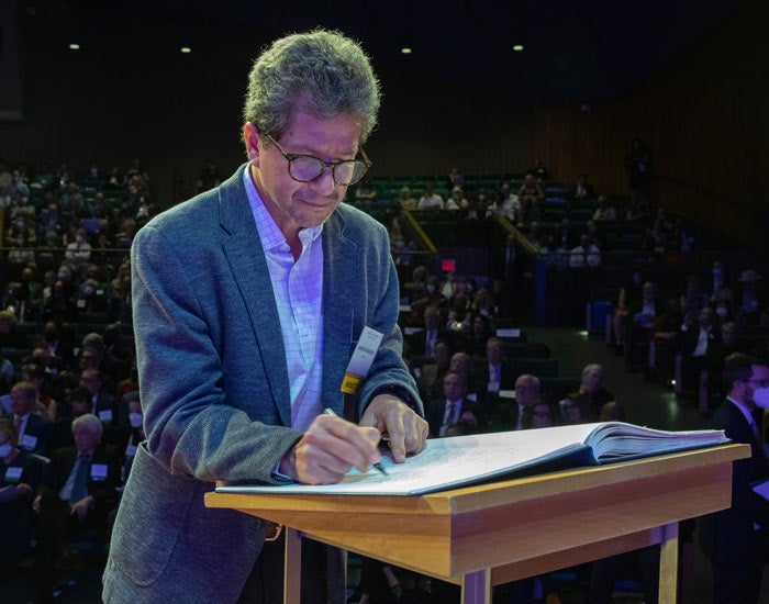 Andrés Reséndez, UC Davis faculty, in suit, signs book, at podium, in front of audience