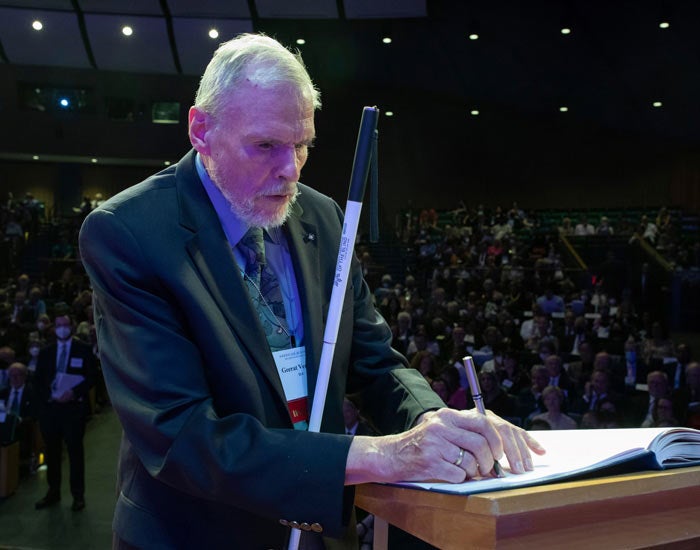 Geerat J. Vermeij, UC Davis faculty, in suit, signs book, at podium, in front of audience