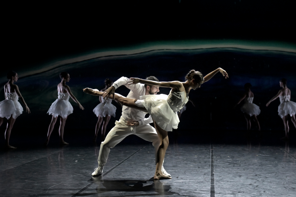 Ballet dancers performing on dark stage 