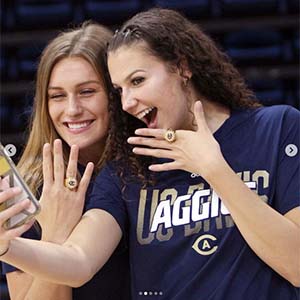 Two basketball players take selfie with championship rings