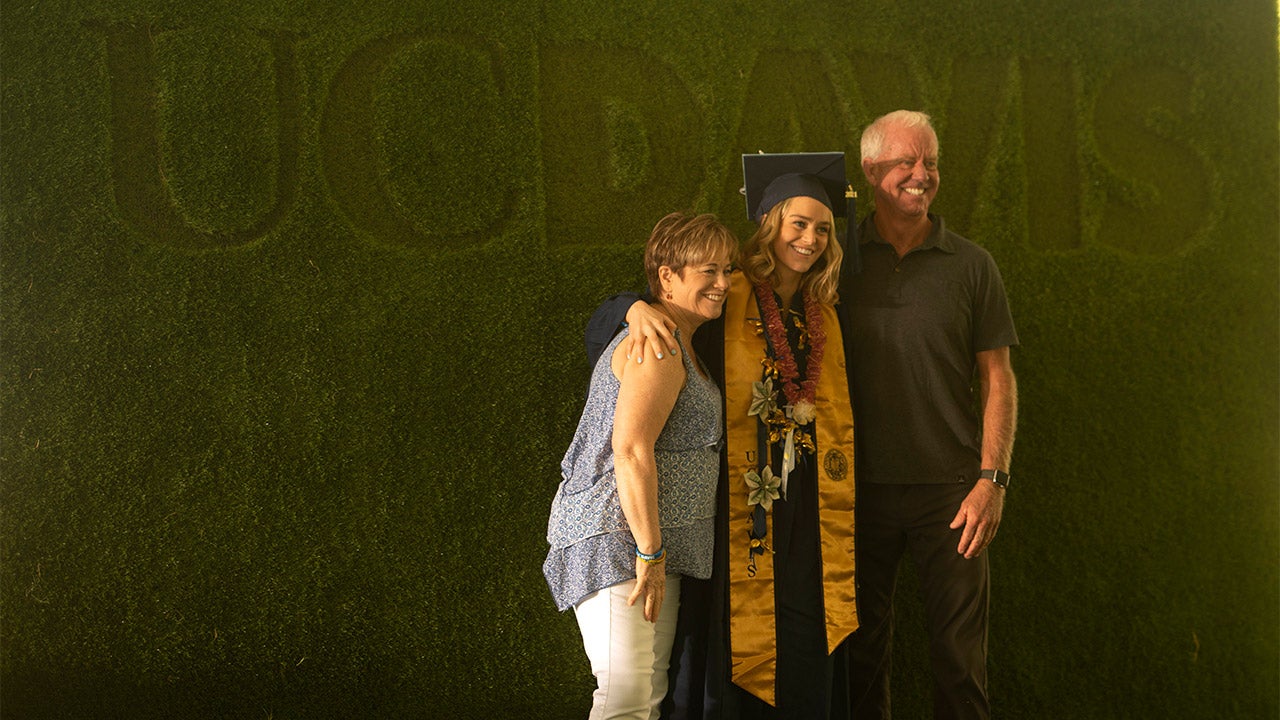 Family poses for photo in front of green backdrop.