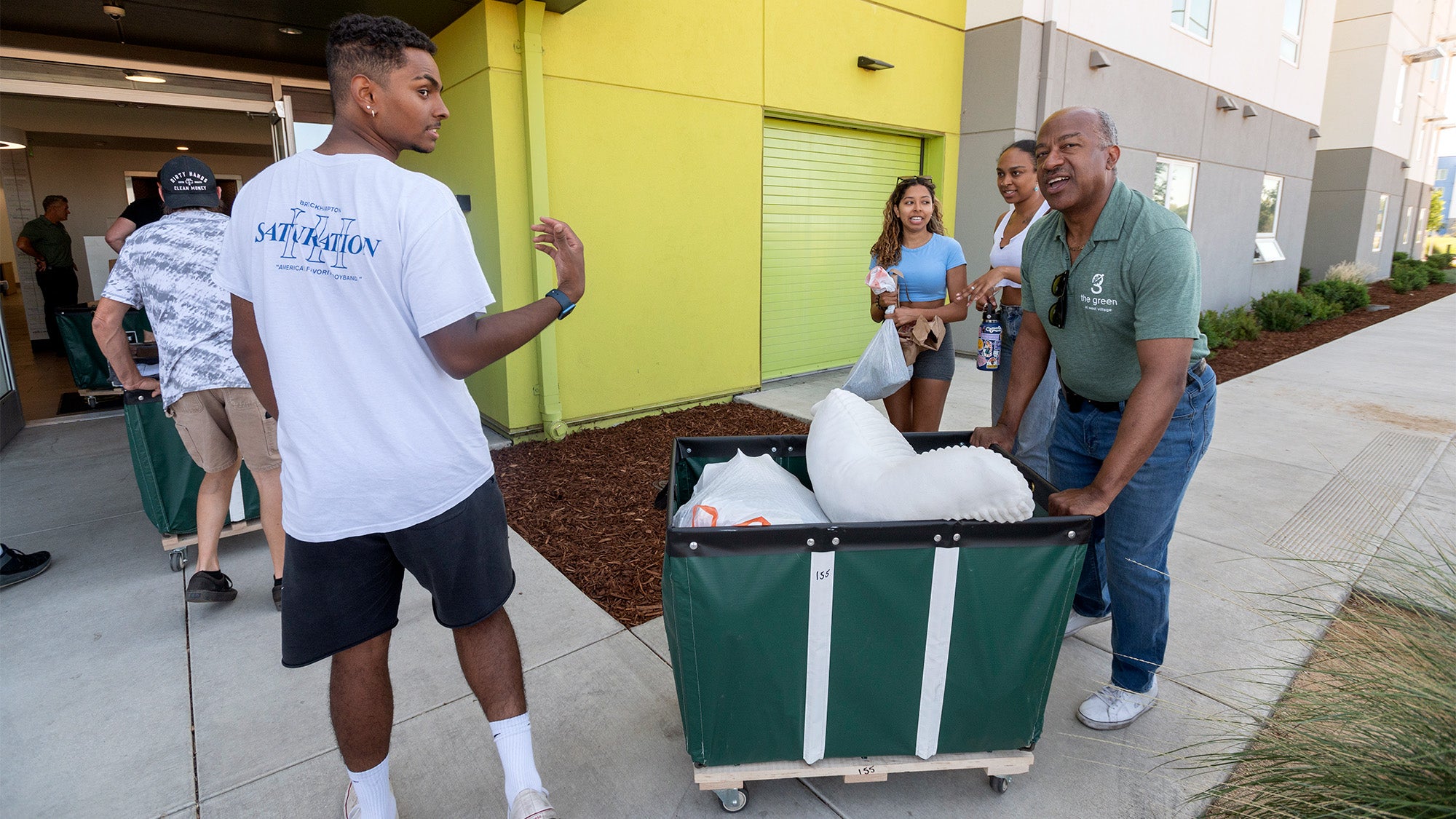 Chancellor Gary S. May pushes a moving cart for a family at The Green.