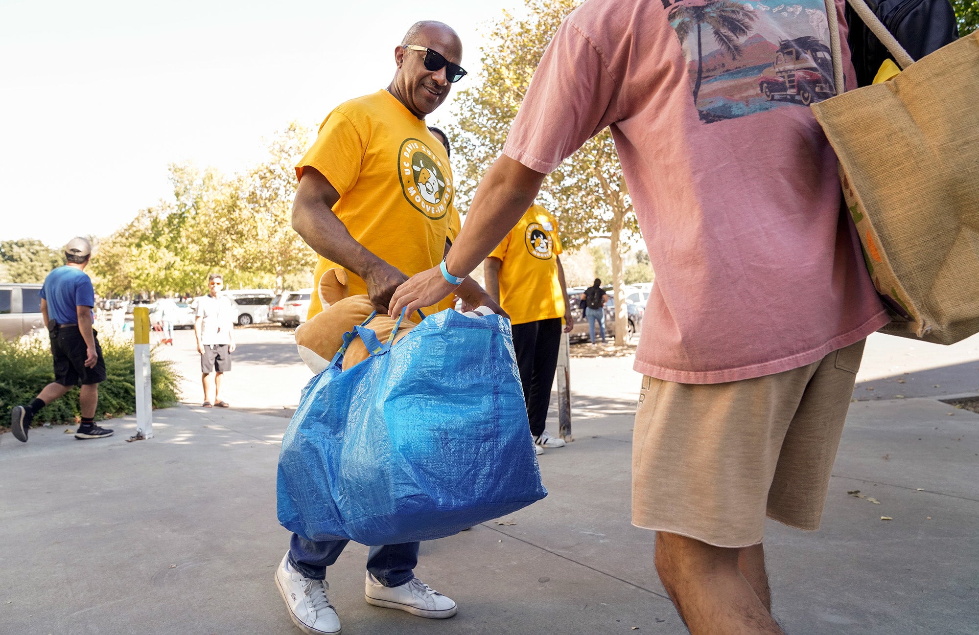 Chancellor Gary S. May takes a blue bag from a student during Moove-In.